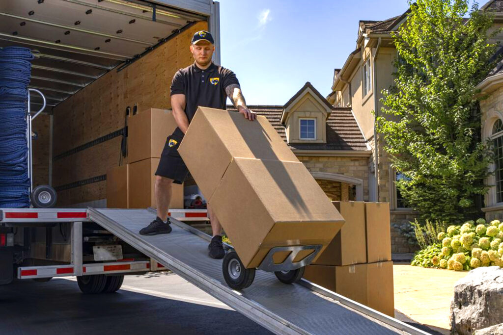 Professional mover unloading moving boxes from a truck at a residential home