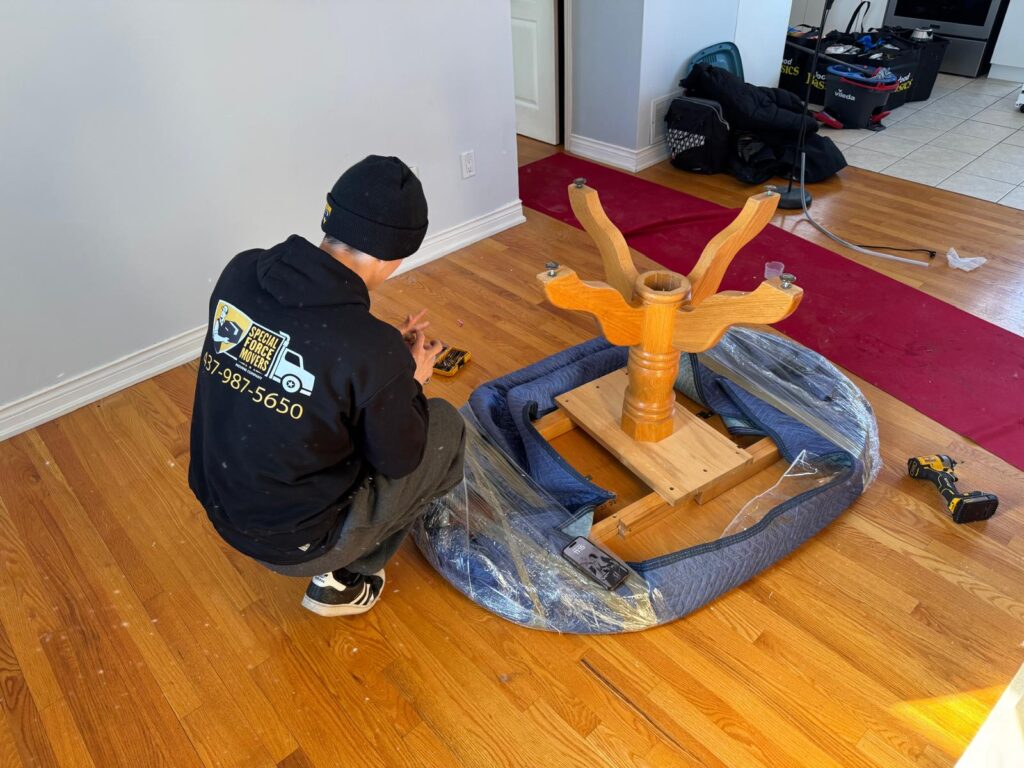 Professional mover disassembling and wrapping furniture for a residential move