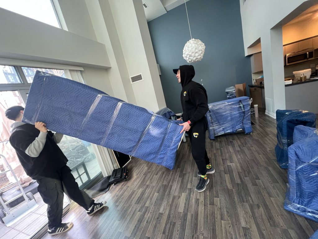 Professional movers safely carrying wrapped furniture during a residential move