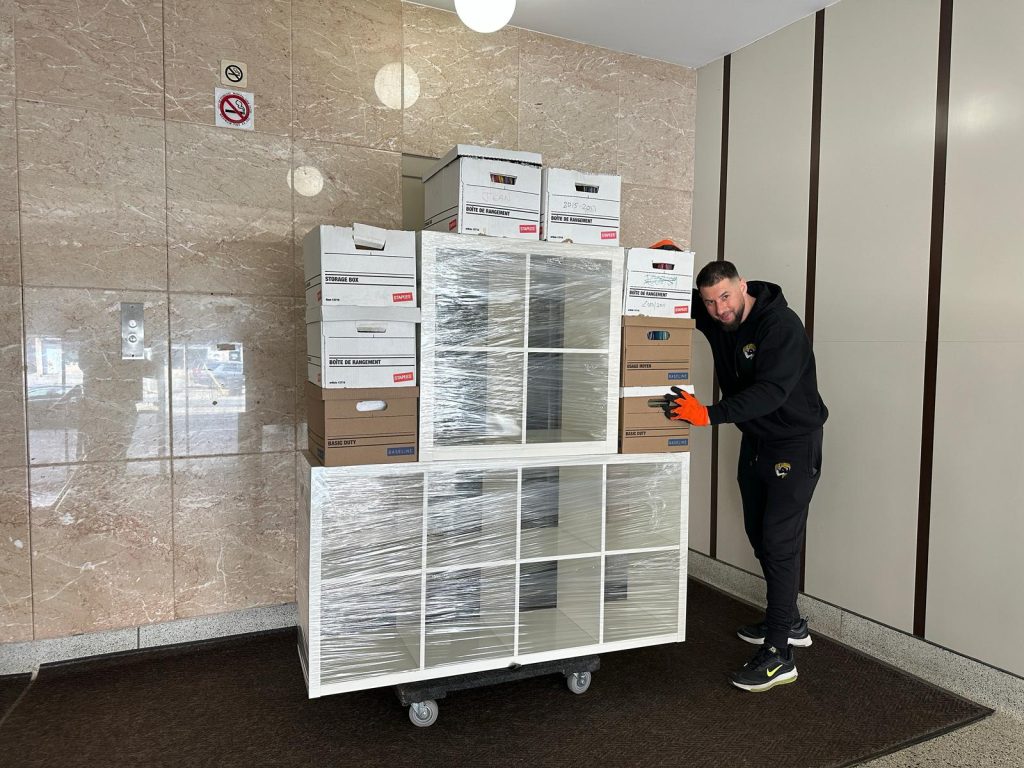 Professional mover with wrapped furniture and moving boxes