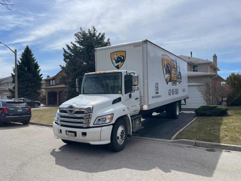 A white moving truck parked outside a house.